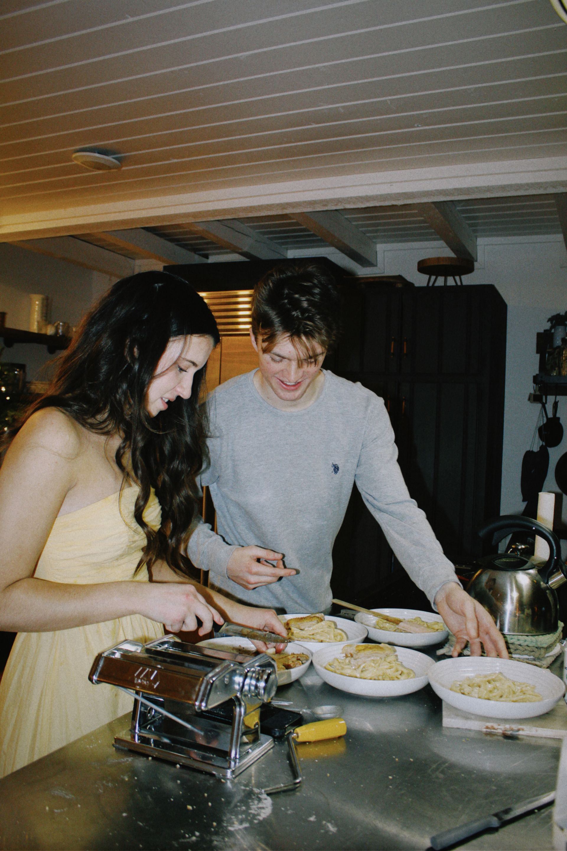 O casal preparando massa fresca na cozinha, com os pratos servidos no balcão