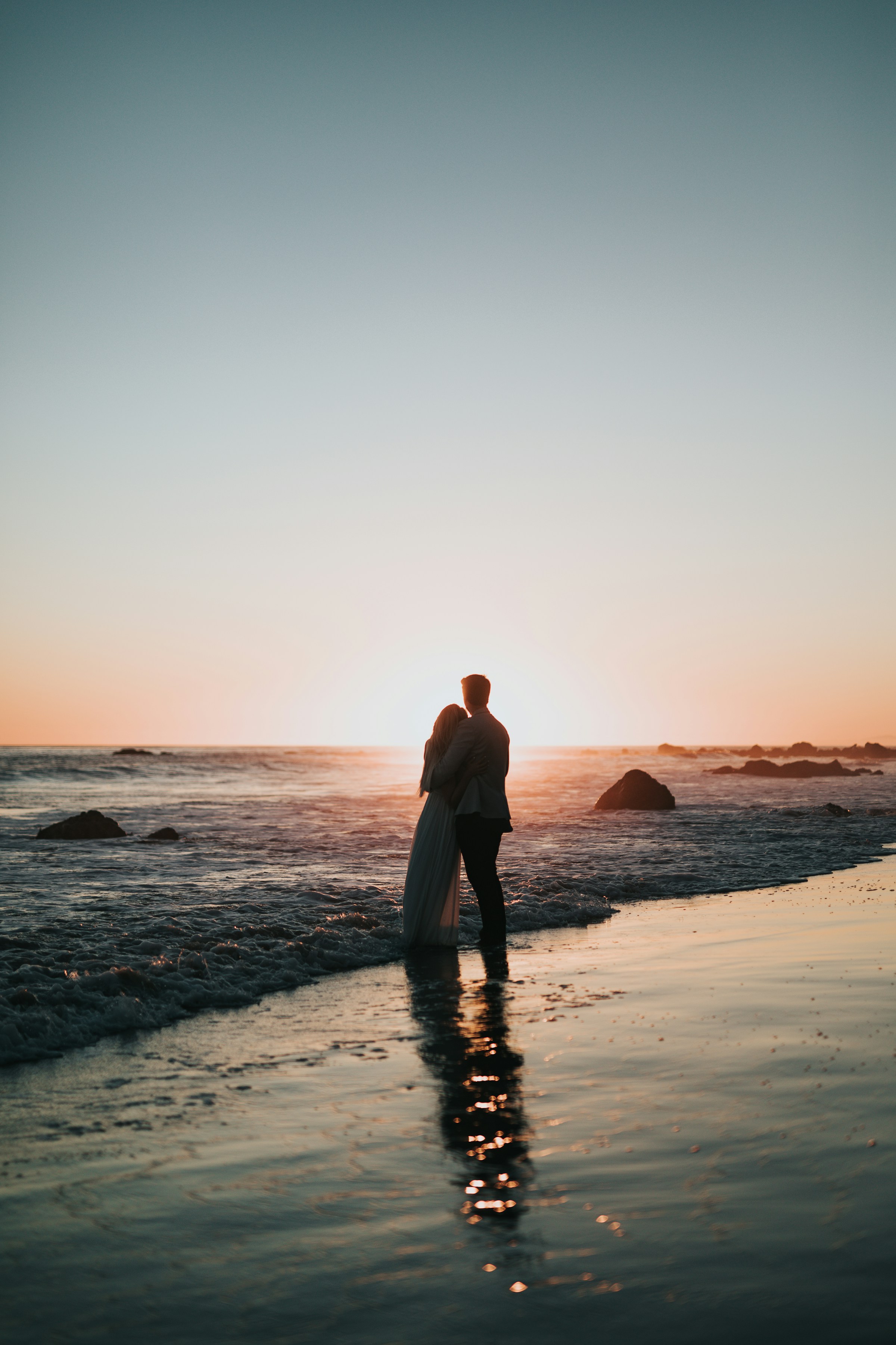 A silhueta do casal abraçado na beira do mar ao entardecer